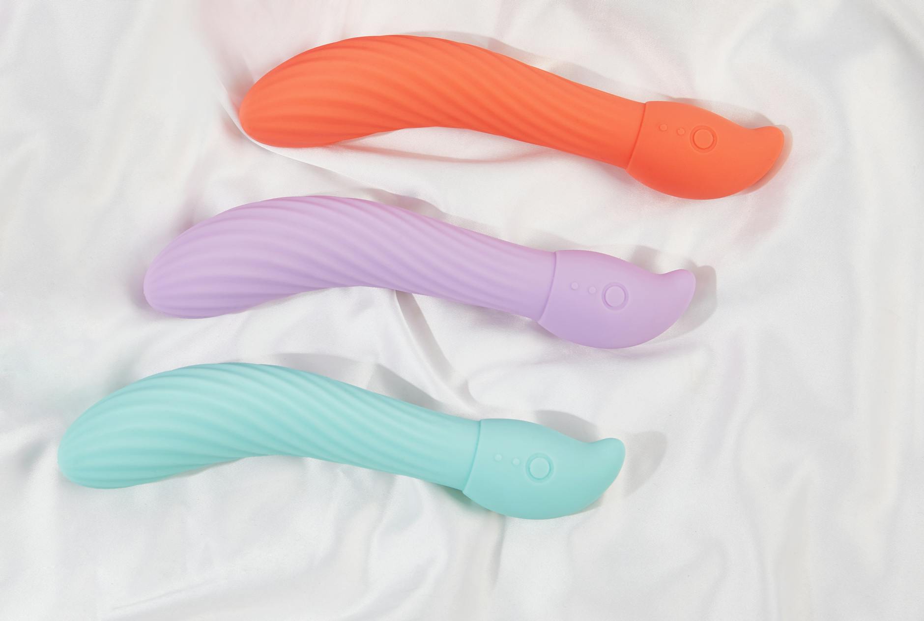 Three colorful vibrators and lemon-shaped toys arranged on white fabric, showing texture and design differences.