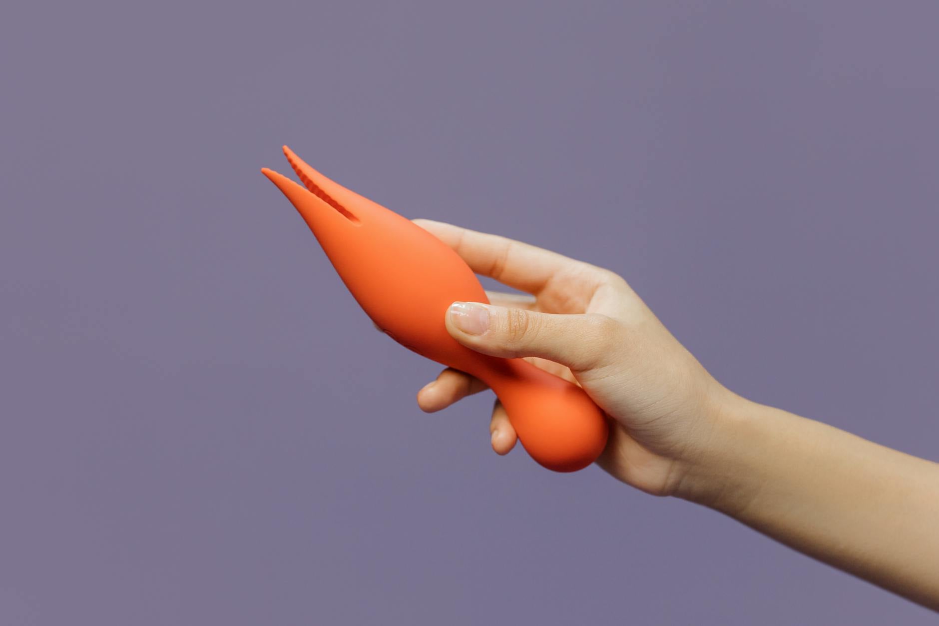Hand holding a lemon vibrator against a minimalist purple backdrop, showcasing modern intimate wellness.