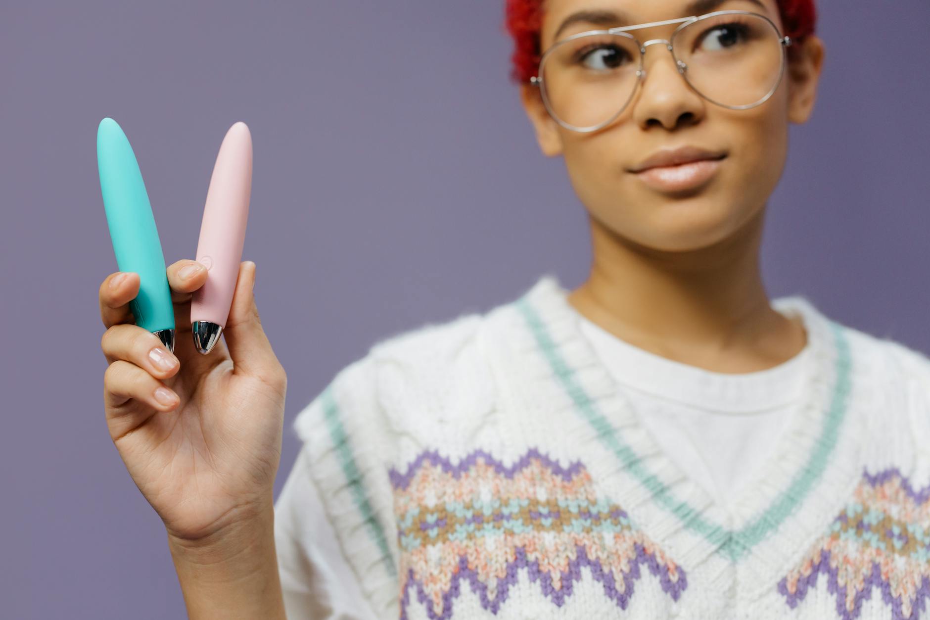 Two colorful vibrators held against a purple background, representing different arousal support options
