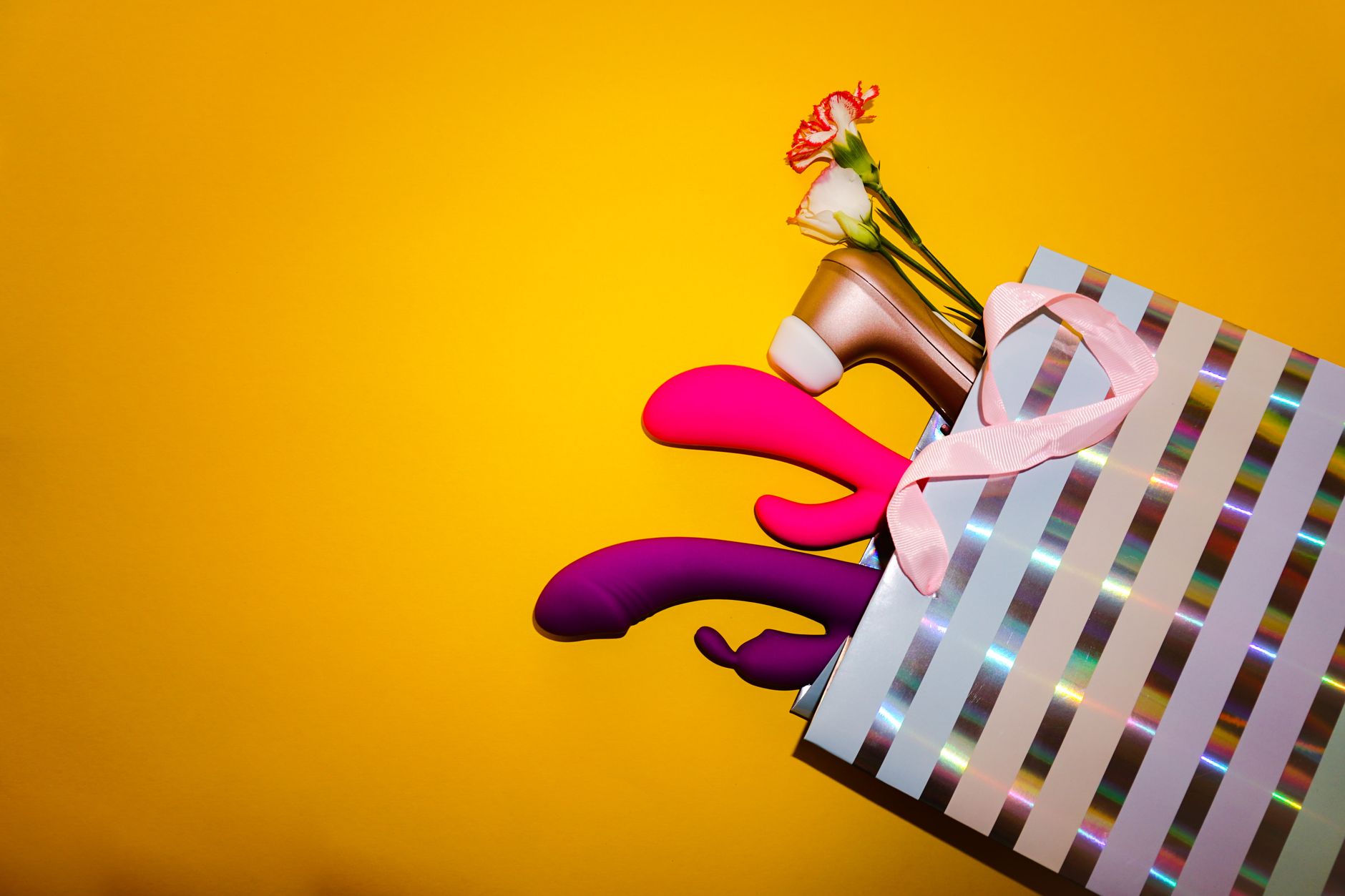 Vibrant collection of adult toys and lemon vibrators arranged in a holographic bag against a bold yellow background.